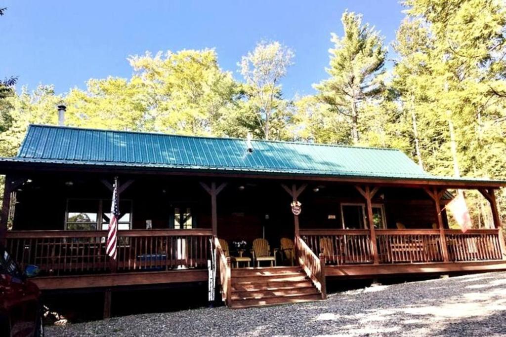 a large wooden cabin with a green roof at Mountain-Top-Hideaway Stay in a log cabin on a private rd! Swim, hike, explore a true mountain experience in North Blenheim