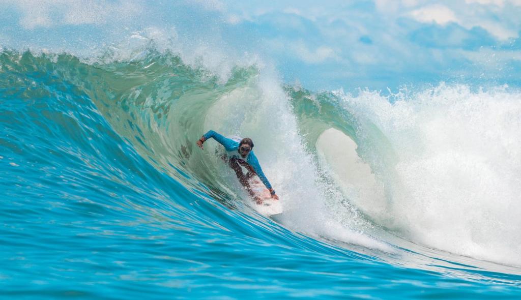 a man riding a wave on a surfboard in the ocean at Surf Synergy All-Inclusive Surf and Wellness Retreat in Jacó