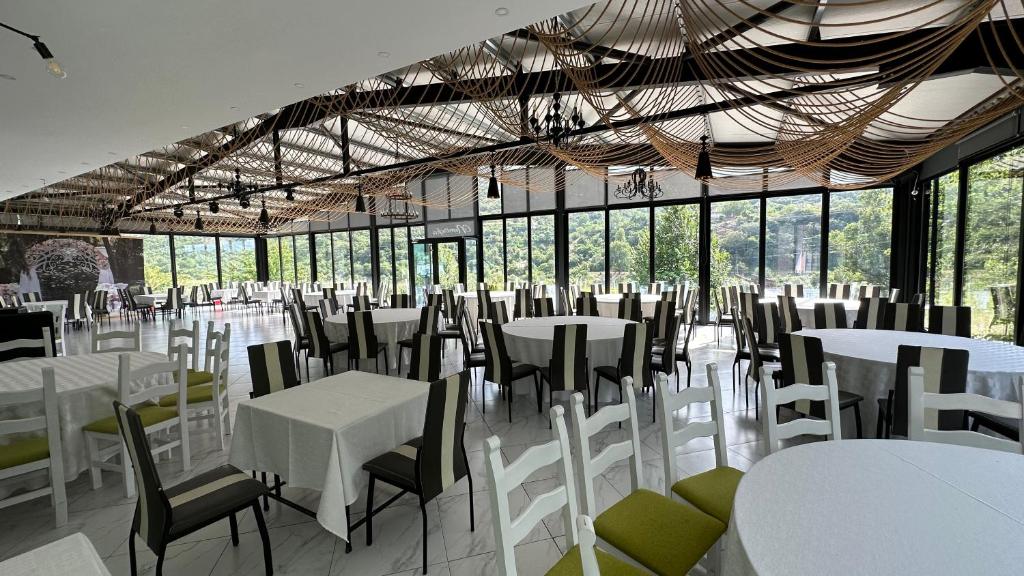een feestzaal met witte tafels, stoelen en ramen bij Hotel Nemercka in Përmet