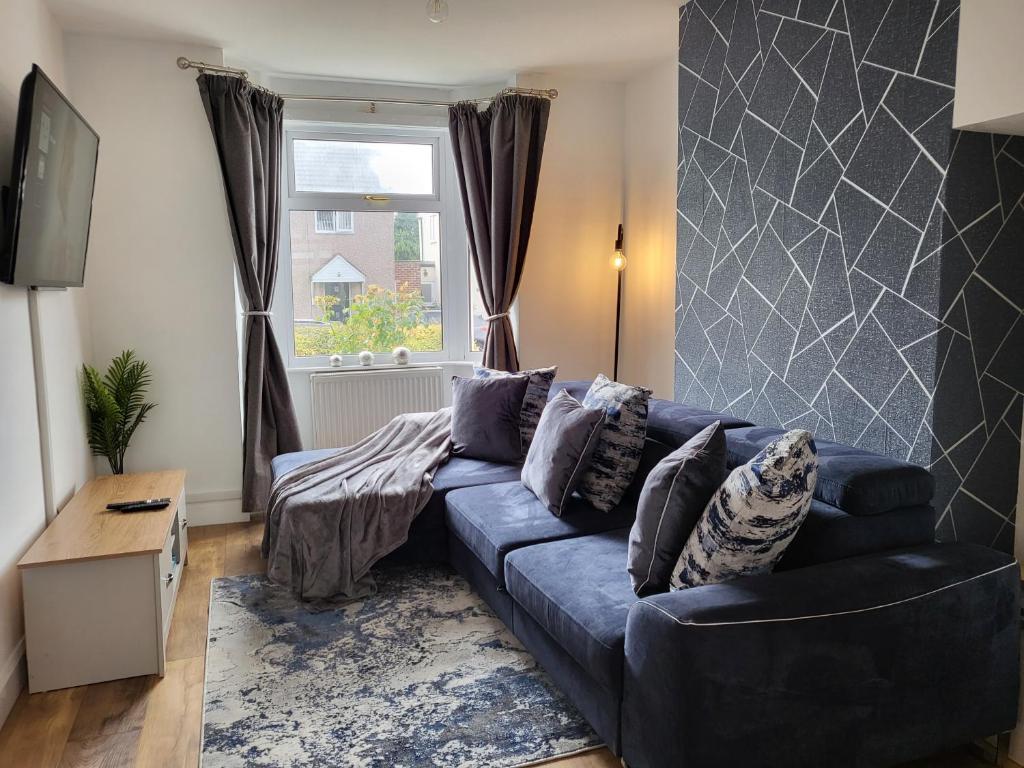 a living room with a blue couch and a window at Coventry Cosy Home - Great location for Contractors, Families, Relocators, close Walsgrave Hospital and Motorways in Wyken