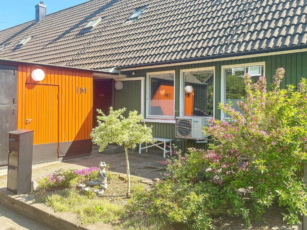 una casa verde y naranja con un perro sentado frente a ella en Holiday home Västervik III en Västervik