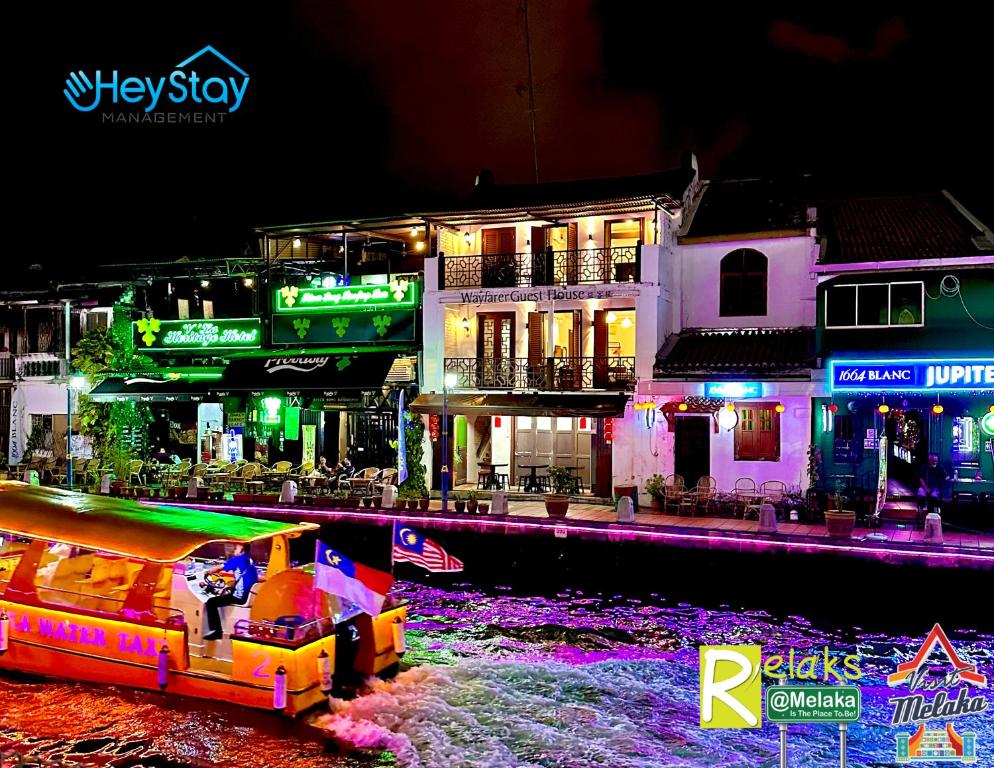 ein Boot im Wasser vor den Gebäuden in der Nacht in der Unterkunft Wayfarer Guest House Jonker Street Melaka By Heystay Management in Malakka