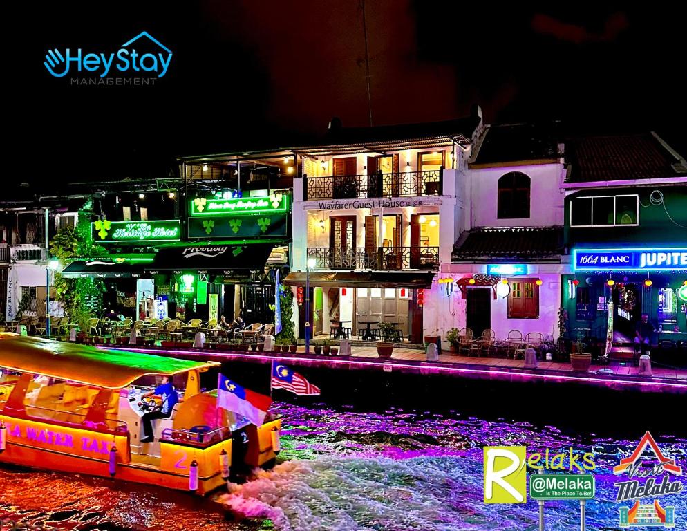 a boat in the water in front of buildings at night at Wayfarer Guest House Jonker Street Melaka By Heystay Management in Melaka