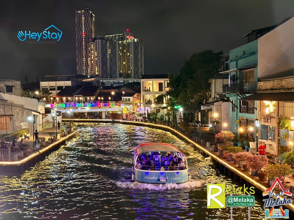 ein Boot auf einem Fluss in einer Stadt nachts in der Unterkunft Wayfarer Guest House Jonker Street Melaka By Heystay Management in Malakka