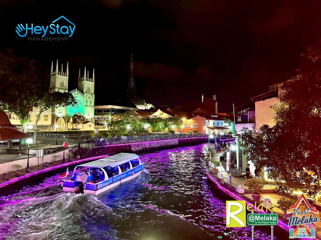 ein Boot, das nachts den Fluss hinunter fährt in der Unterkunft Wayfarer Guest House Jonker Street Melaka By Heystay Management in Malakka