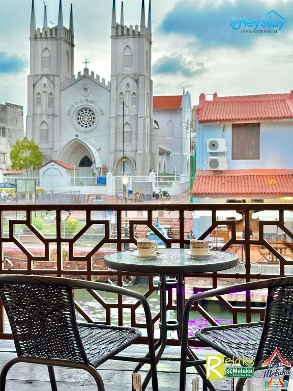 eine Terrasse mit Tischen und Stühlen vor einer Kirche in der Unterkunft Wayfarer Guest House Jonker Street Melaka By Heystay Management in Malakka