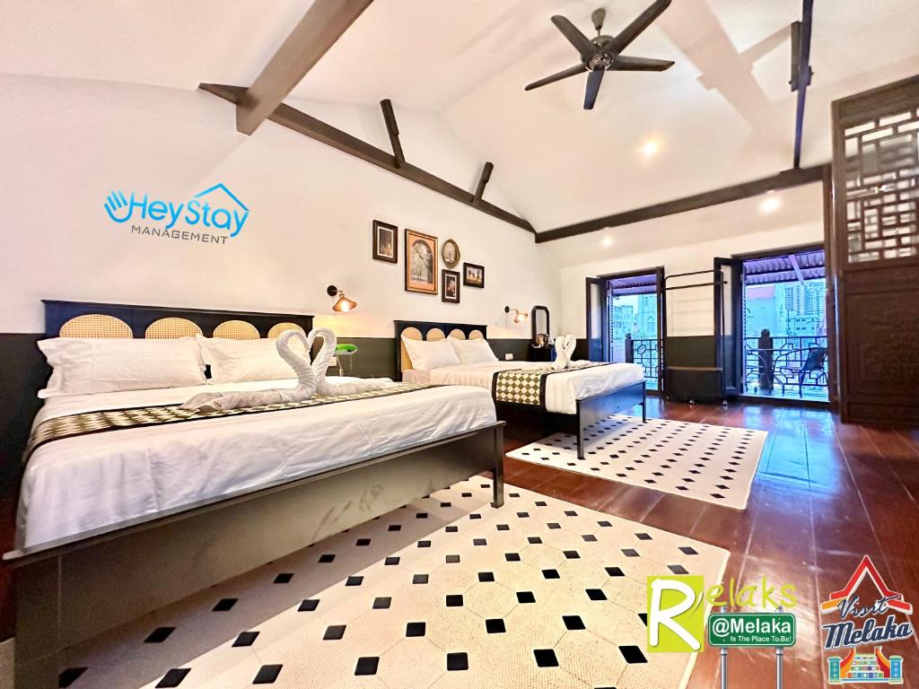 ein Schlafzimmer mit zwei Betten und einem Deckenventilator in der Unterkunft Wayfarer Guest House Jonker Street Melaka By Heystay Management in Malakka