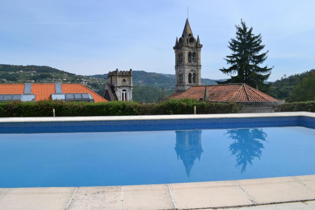 una piscina di fronte a un edificio con torre dell'orologio di Casa da Quinta da Calçada a Cinfães