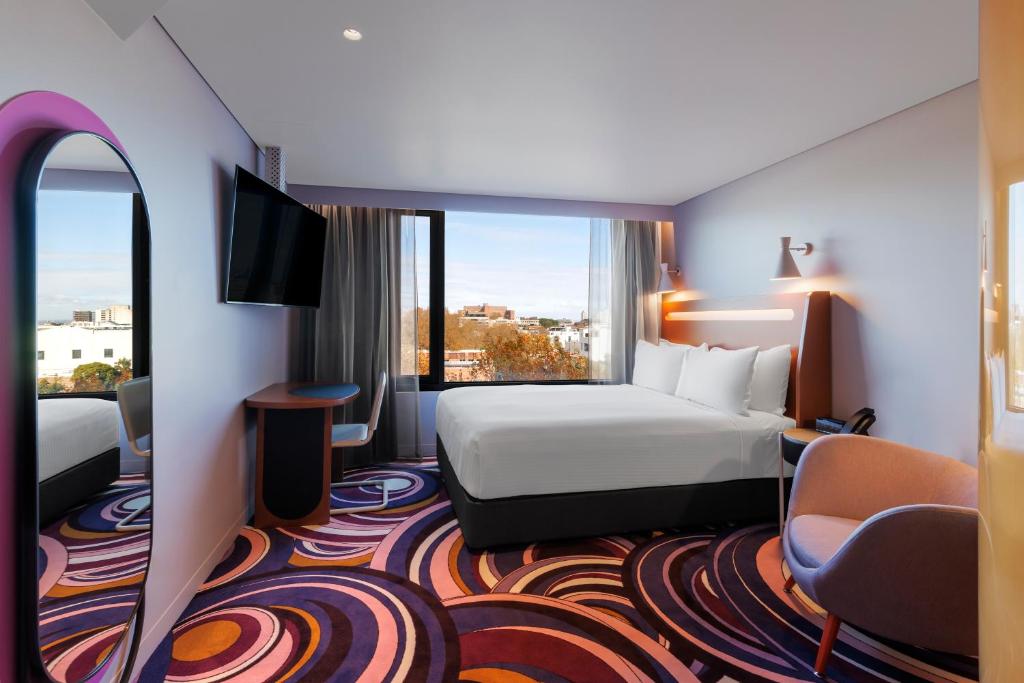 a hotel room with a bed and a large window at Adge Hotel and Residences in Sydney