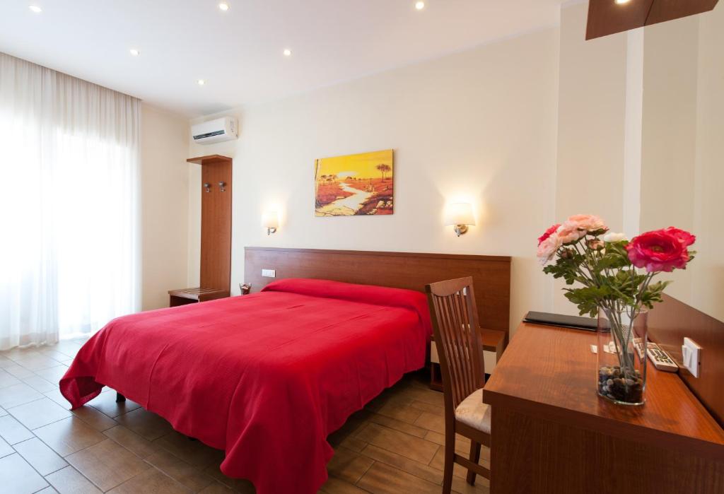 ein Schlafzimmer mit einem roten Bett und einem Tisch mit einer Blumenvase in der Unterkunft Alba Romana in Rom