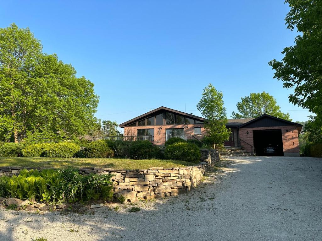 a house with a stone wall in front of a driveway at Amazing view of 4 bedrooms, 3 bathrooms 4-season cottage in Wiarton