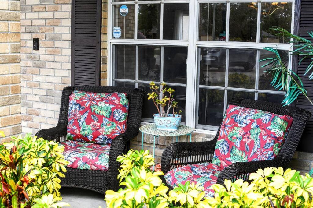 2 chaises en osier avec des oreillers colorés assises sur une terrasse couverte dans l'établissement Home, Sweet Home., à Deltona