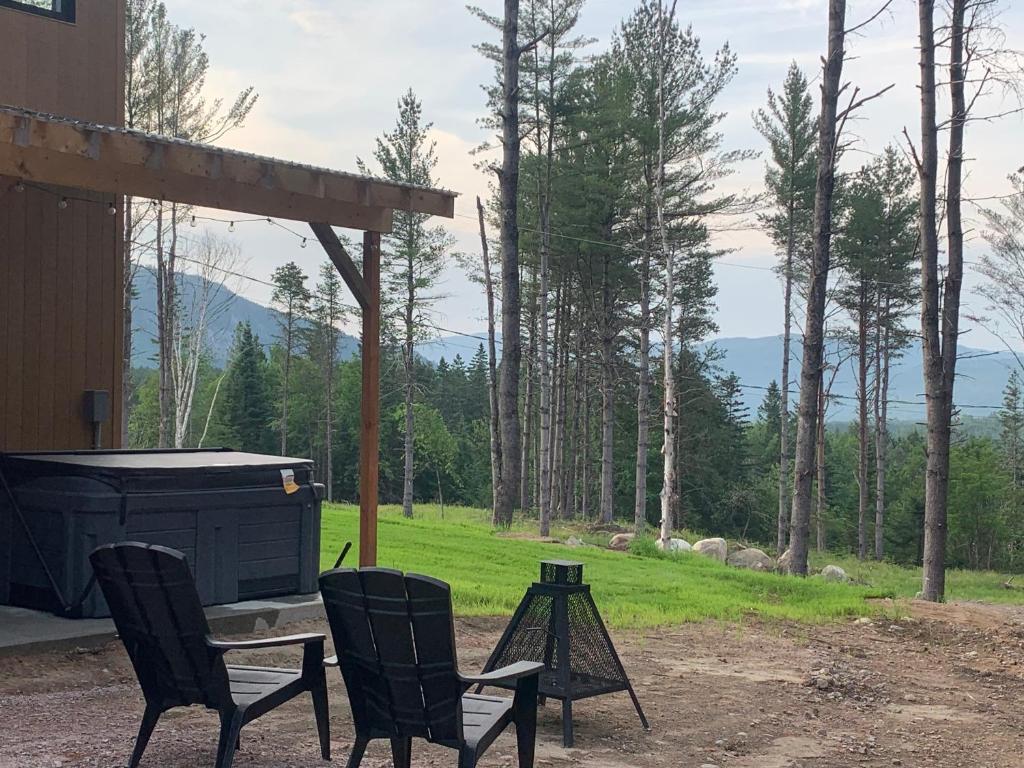 a patio with two chairs and a grill and trees at Vallée bras du Nord Jumeau #1 avec spa in Saint-Raymond
