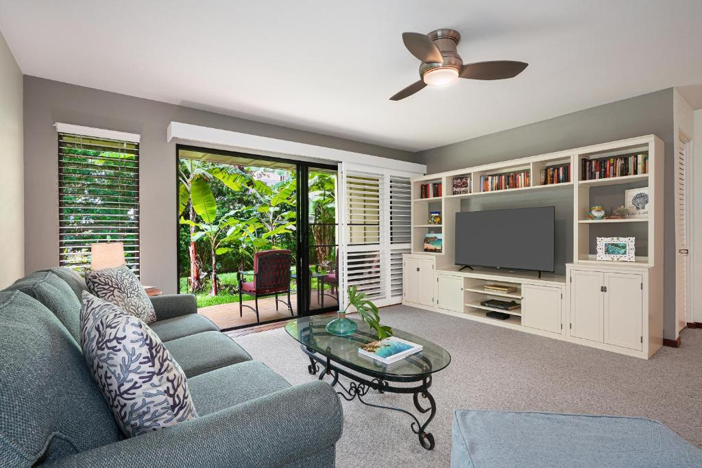 a living room with a blue couch and a tv at Waikomo Streams 203 in Koloa