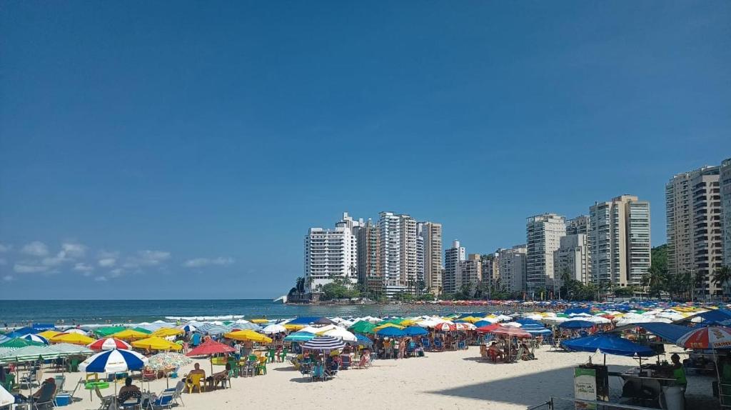 una playa con muchas sombrillas de colores y el océano en Apartamento Edifício Arpoador (Praias Asturias-Tombo), en Guarujá