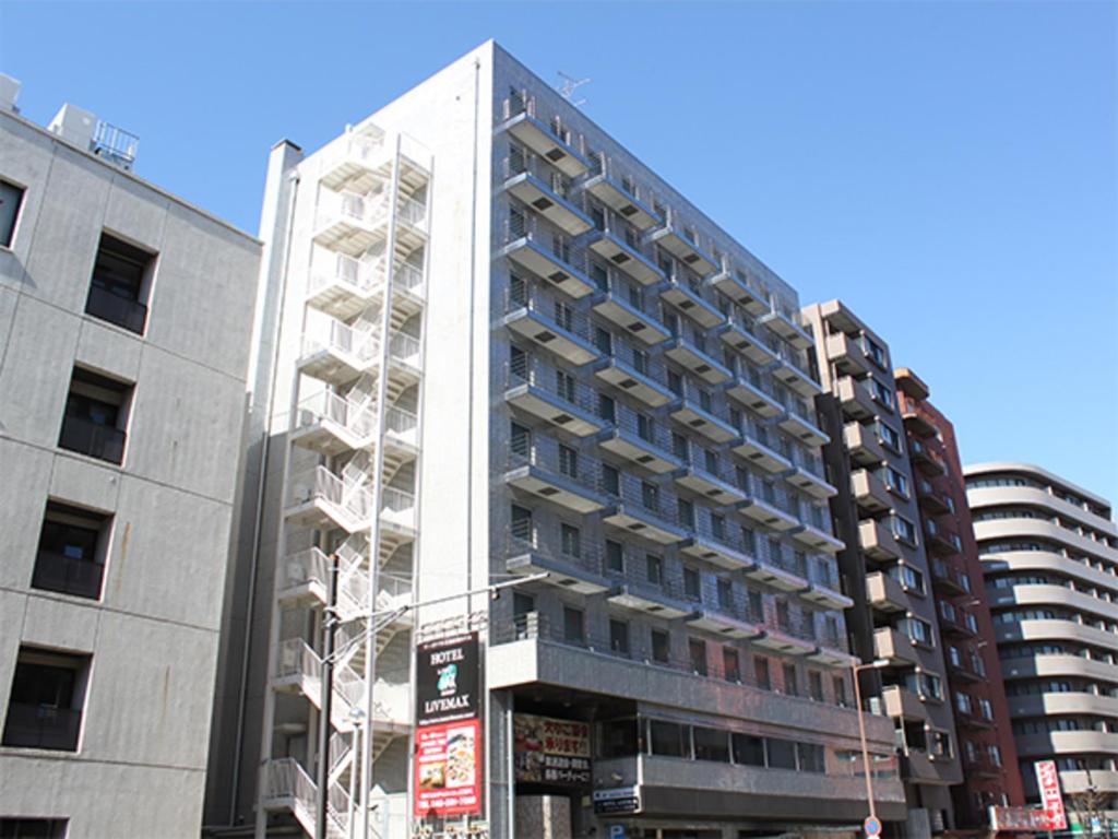 een hoog wit gebouw in een stadsstraat bij HOTEL LiVEMAX BUDGET Yokohama Tsurumi in Yokohama