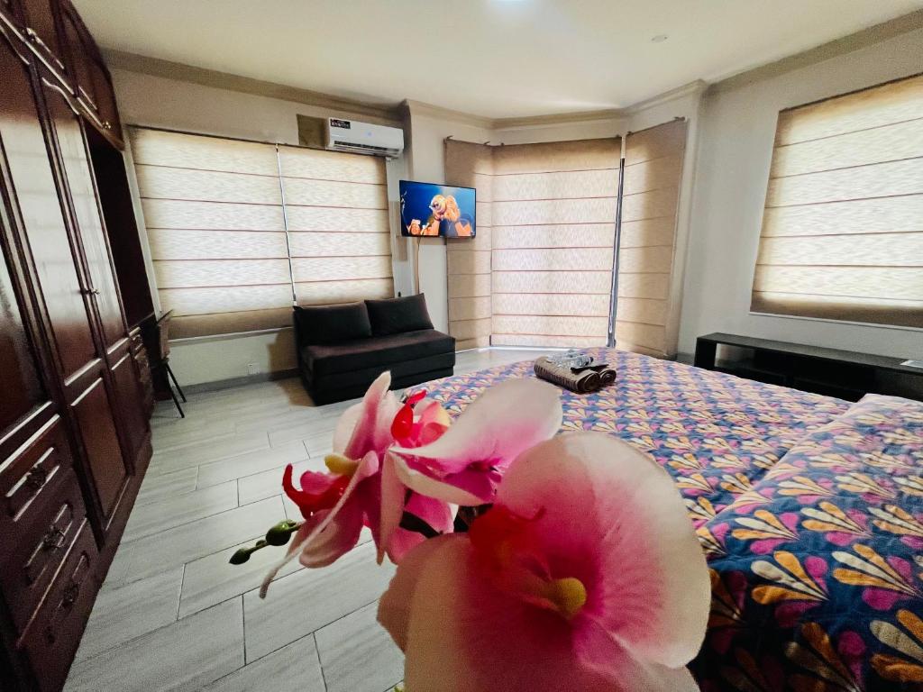 Master Suite Next To San Marino Shopping, Balcony في غواياكيل: غرفة نوم مع سرير مع زهور وردية عليه