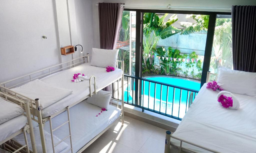 a room with two beds and a balcony with a pool at Bed Station Hostel & Pool Bar Hội An " Former Sunflower" in Hoi An
