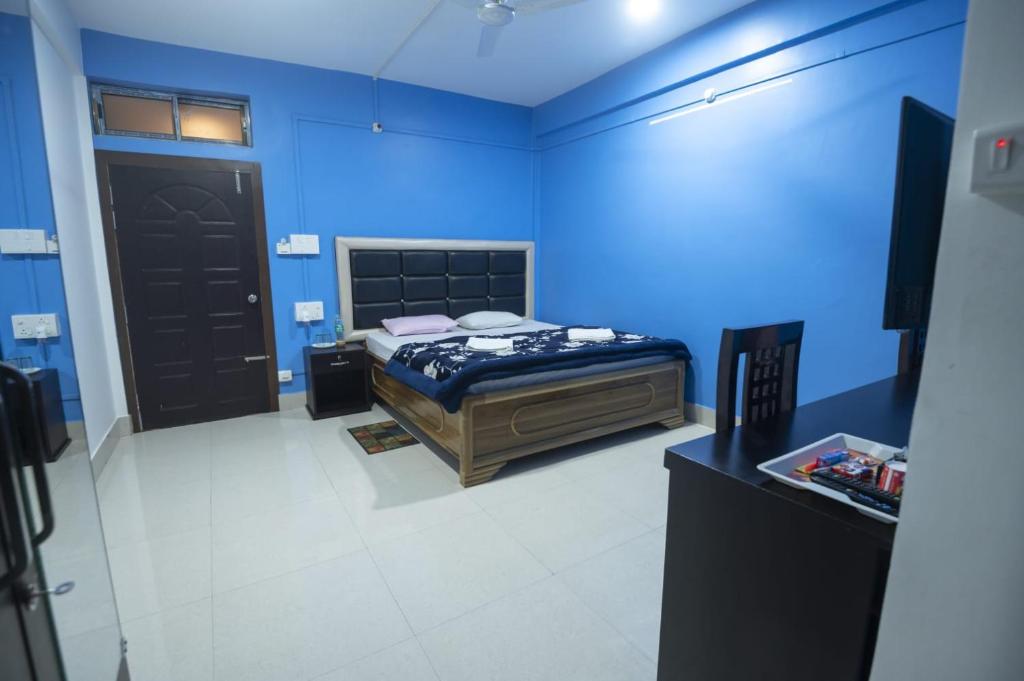 Zimmer mit einem Bett in einem blauen Zimmer in der Unterkunft Jungle Eco Mansion in Kāziranga