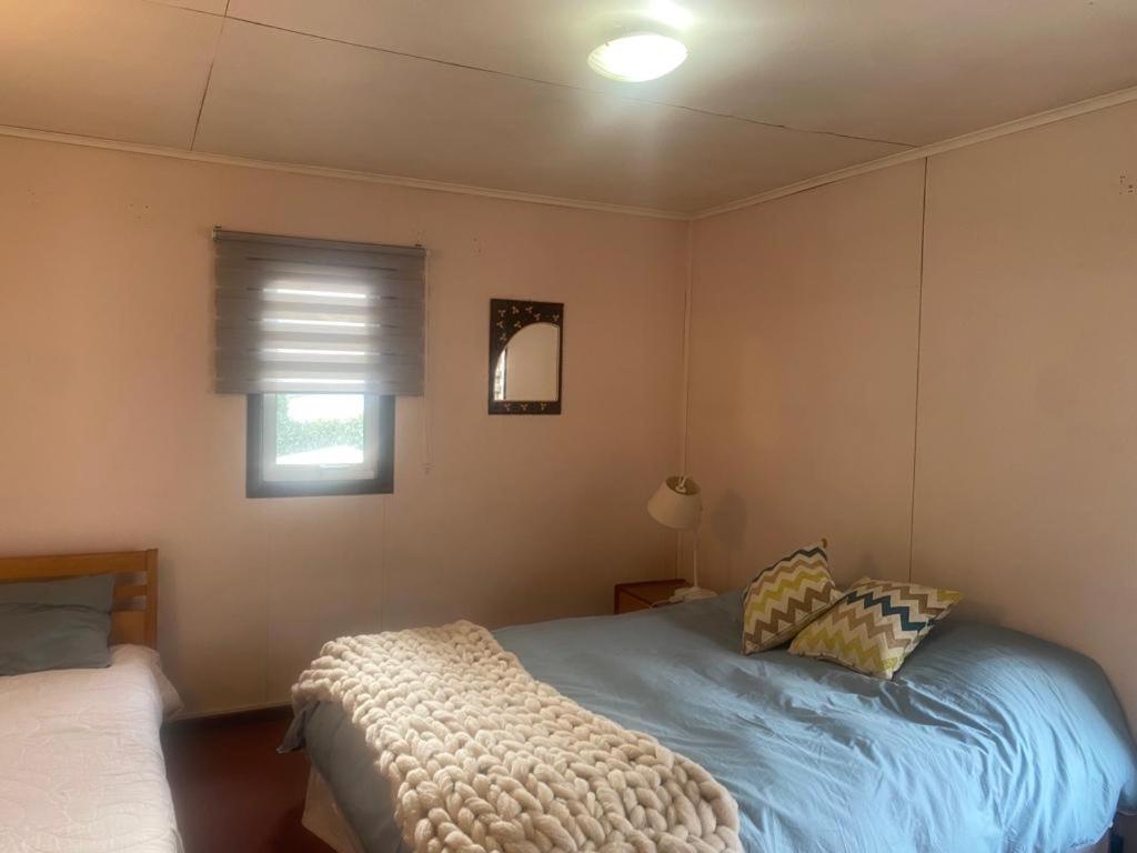 een slaapkamer met een bed en een raam bij HOSTAL AONKEN in Coihaique