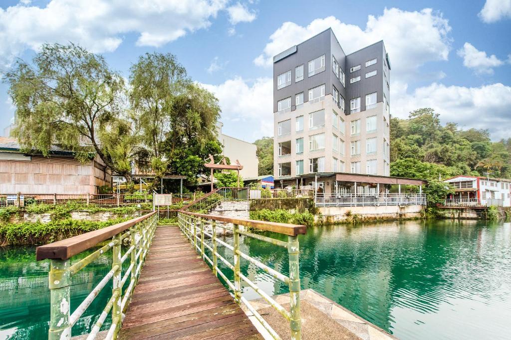 eine Brücke über einen Wasserkörper mit einem Gebäude in der Unterkunft H& 日月潭水漾 l 伊達邵老街 l 湖景 in Yuchi