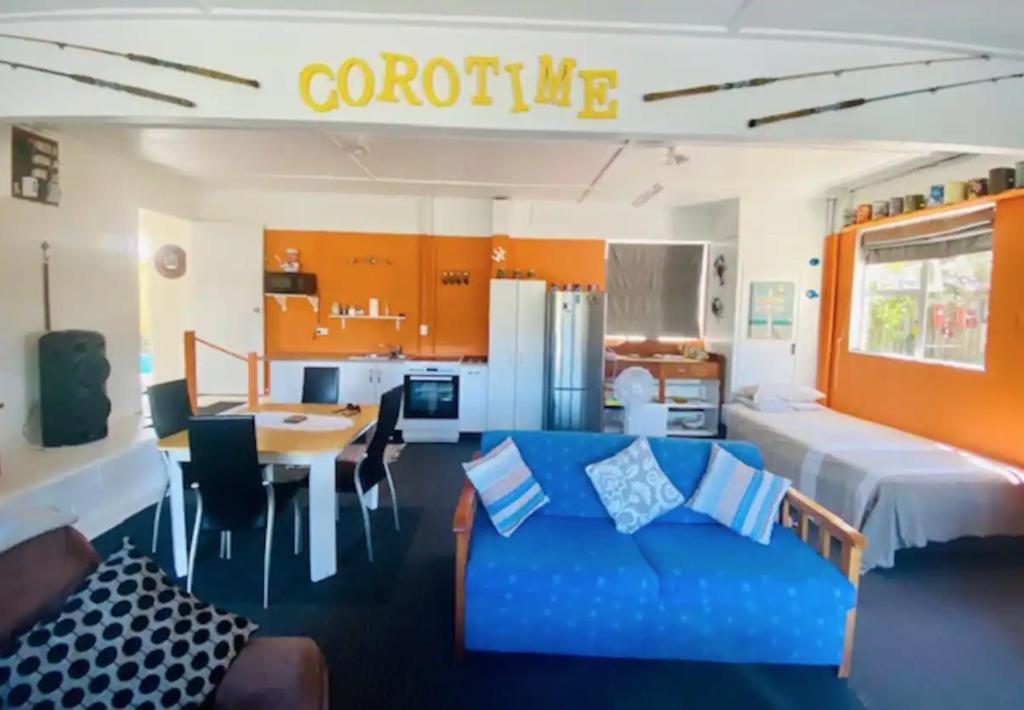 a living room with a blue couch and a table at Corotime ~ Boat Parking ~ Pet Friendly in Coromandel Town