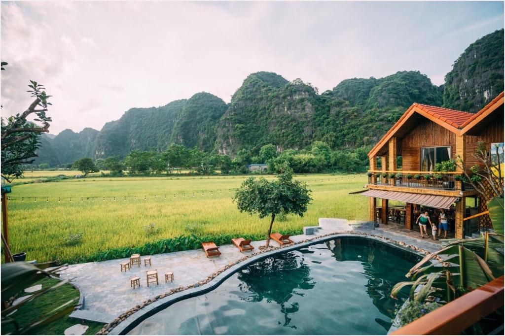 a house with a swimming pool in front of a field at Tam Coc Windy Fields in Ninh Binh