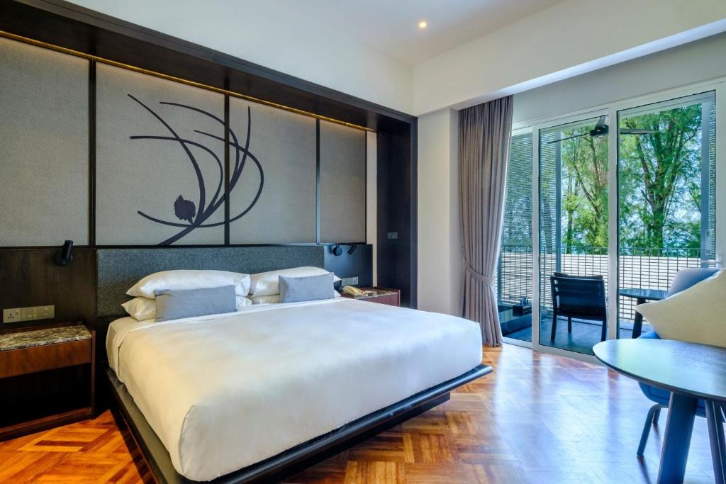ein Schlafzimmer mit einem großen weißen Bett und einem Balkon in der Unterkunft Lone Pine, Penang, a Tribute Portfolio Resort in Batu Feringgi