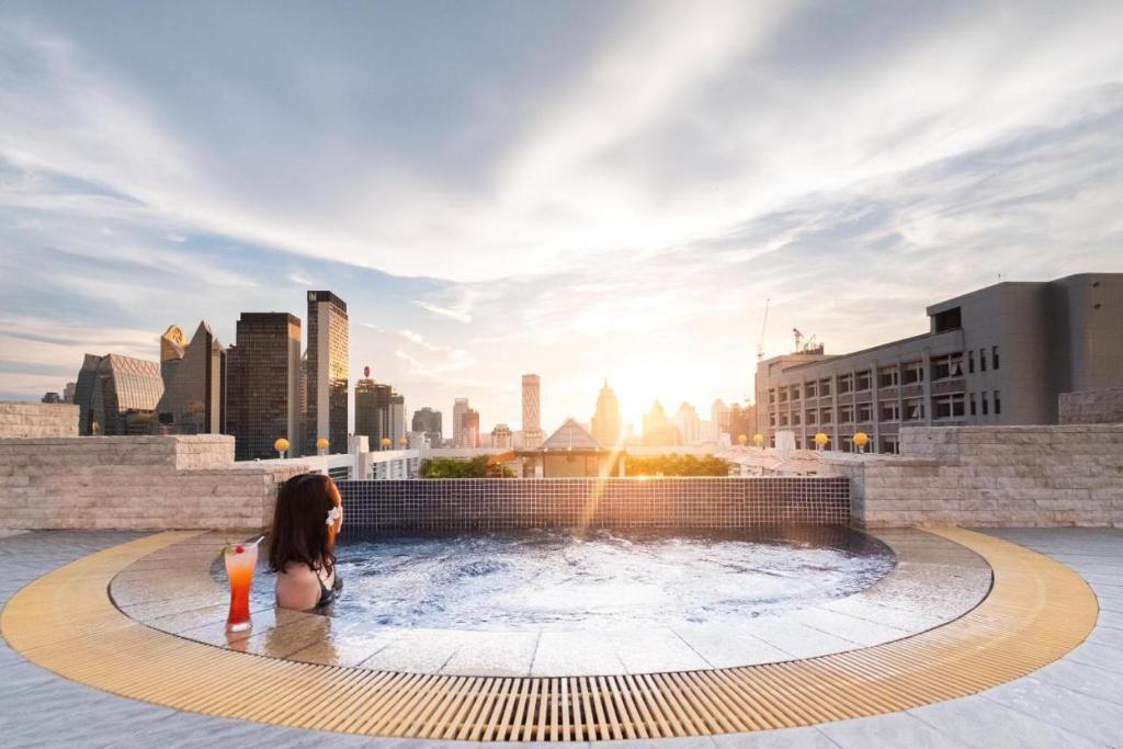 a woman sitting in a hot tub in a city at Zenith Sukhumvit Hotel - SHA Extra Plus in Bangkok