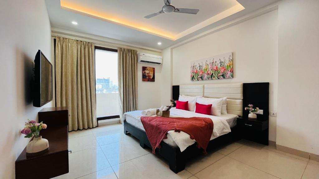 - une chambre avec un grand lit et des oreillers rouges dans l'établissement BluO 3BHK Golf Course Road - Balcony, Lift, Terrace, à Gurgaon