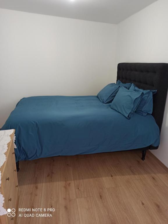 een bed met een blauw dekbed en kussens erop bij Le Petit Cosy in Saint-Front-la-Rivière