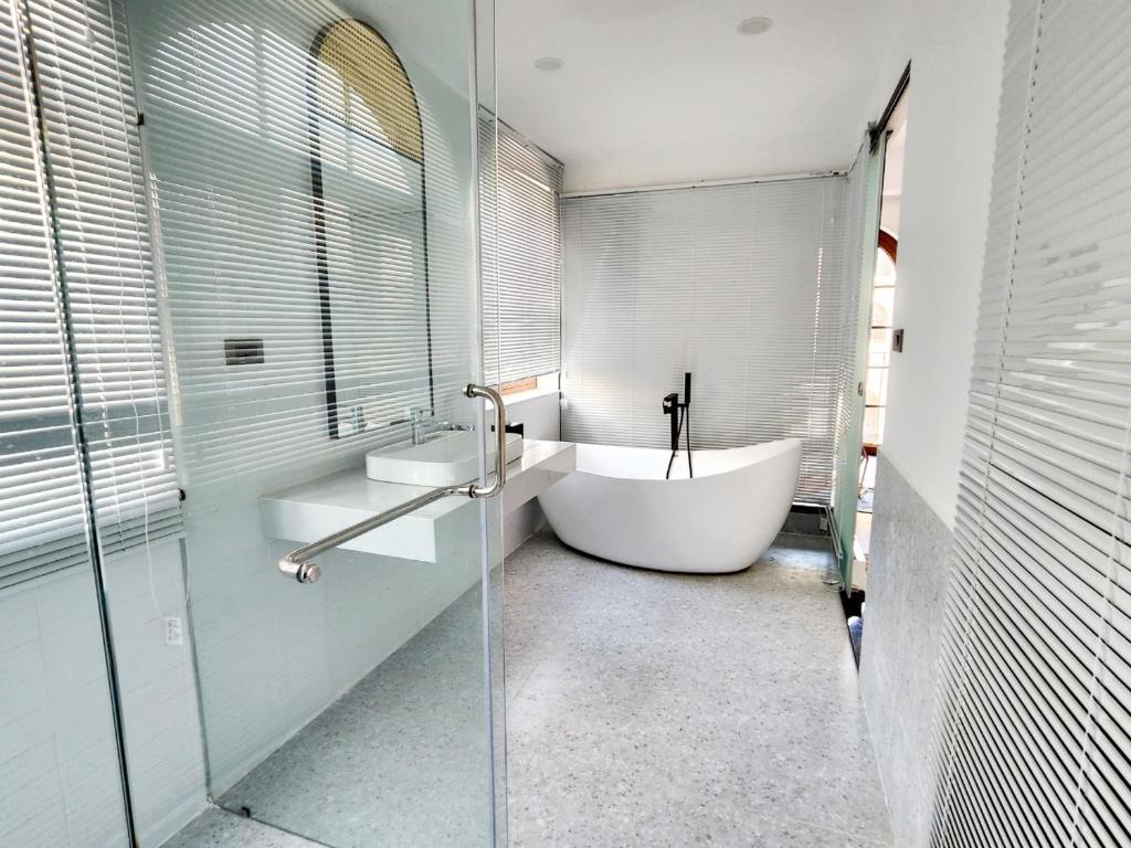 a white bathroom with a tub and a sink at LITTLE PHU QUOC STUDIO in Phu Quoc