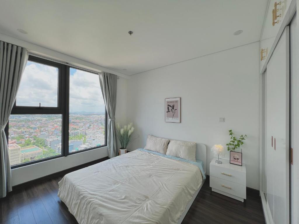 um quarto branco com uma cama e uma grande janela em Lucy Homestay - Hoàng Huy Grand Tower em An Lạc