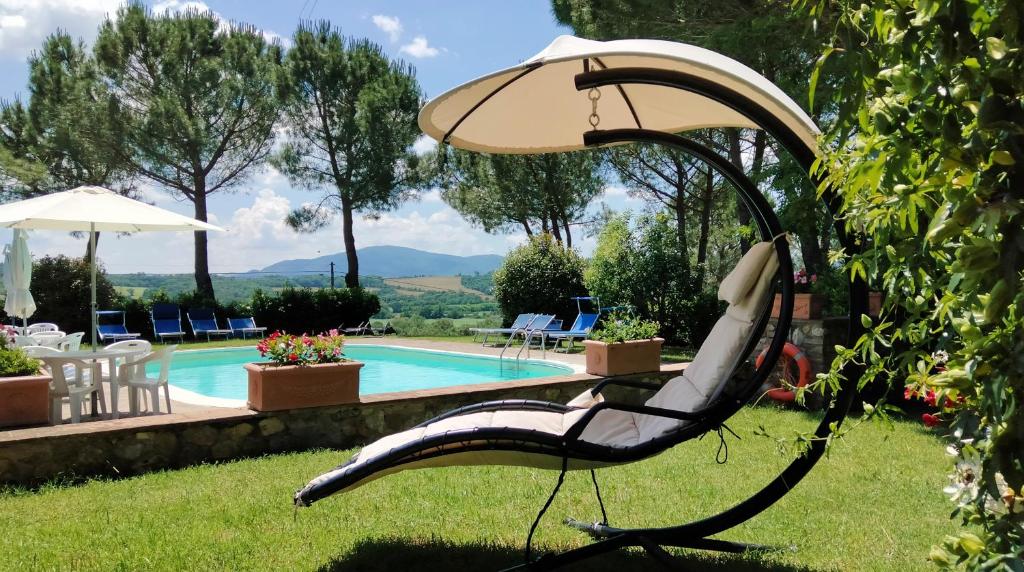 una silla en el césped junto a una piscina en Agriturismo Il Catrino, en Ponteginori