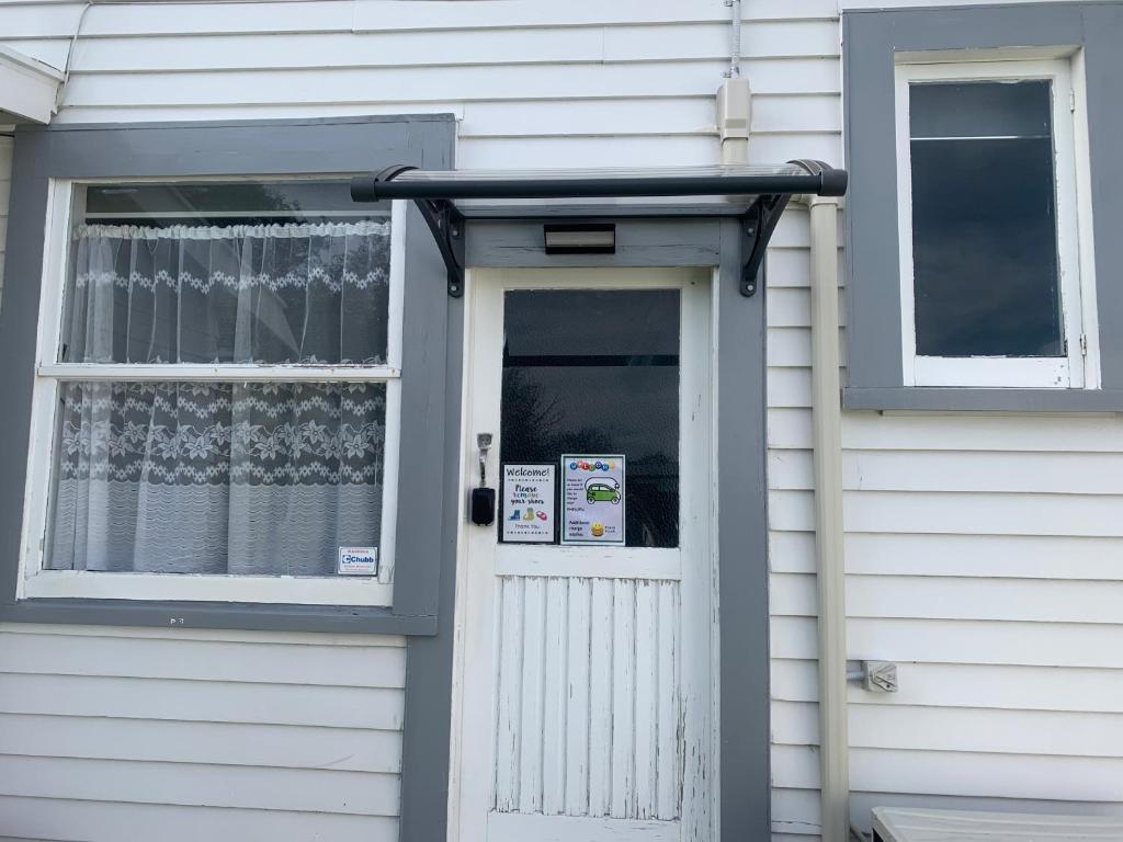 a white house with a door and a window at RL Two-Bedroom Apartment in Palmerston North