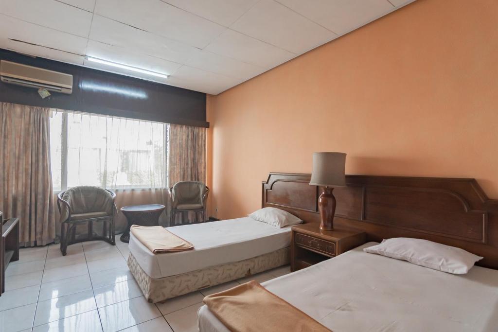 Postel nebo postele na pokoji v ubytování Istana Hotel Bandung Mitra RedDoorz
