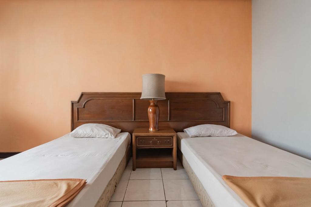 Postel nebo postele na pokoji v ubytování Istana Hotel Bandung Mitra RedDoorz