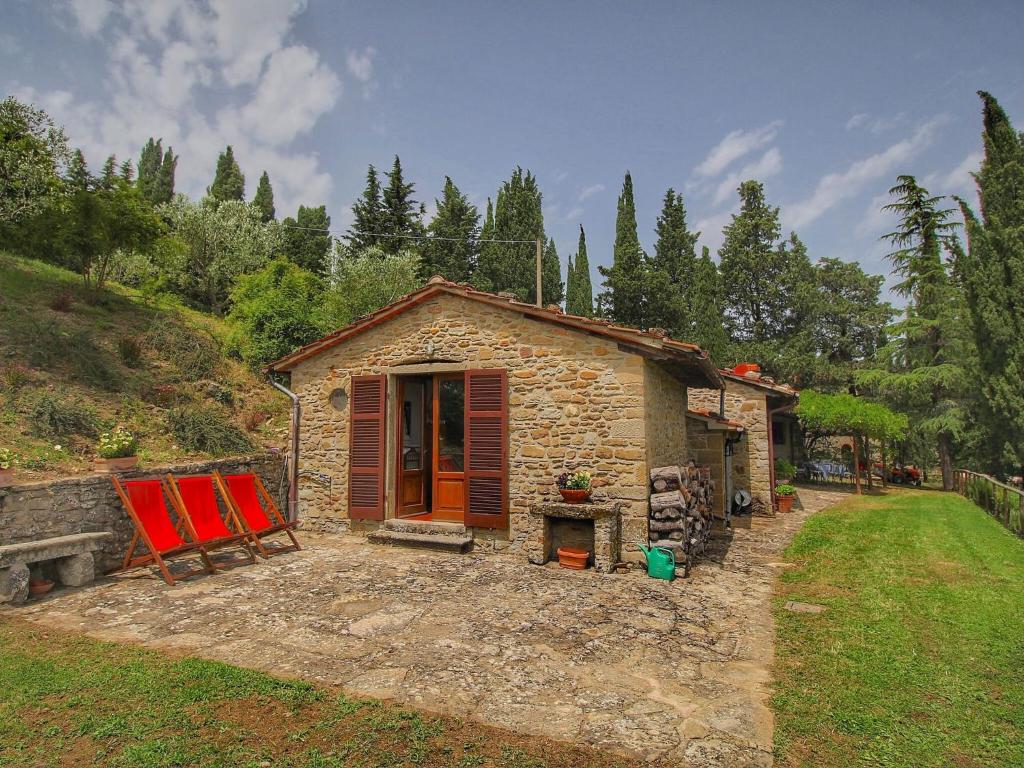 uma pequena casa de pedra com duas cadeiras vermelhas ao lado em Cottage La Stefania near Anghiari in beautiful setting em Misciano