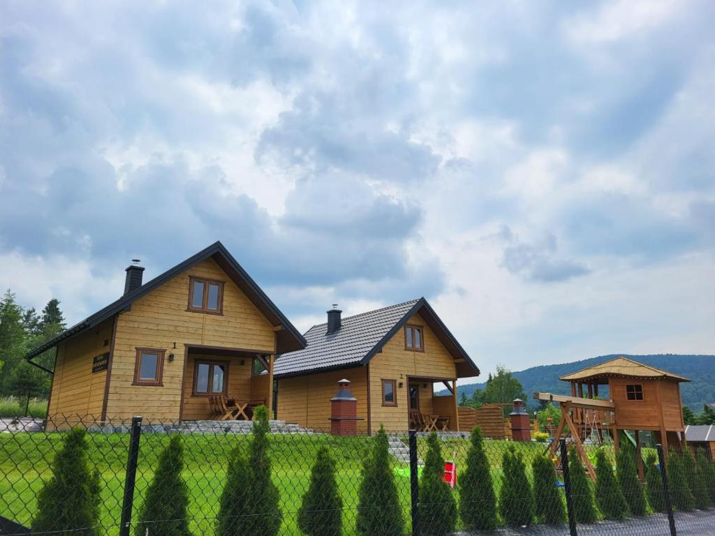 une maison en bois avec une clôture devant elle dans l'établissement Domki Pod Beskidem, à Wysowa-Zdrój