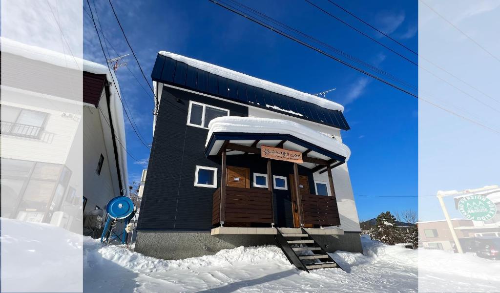 a small building with snow on the side of it at Furano Yukisachi House in Furano