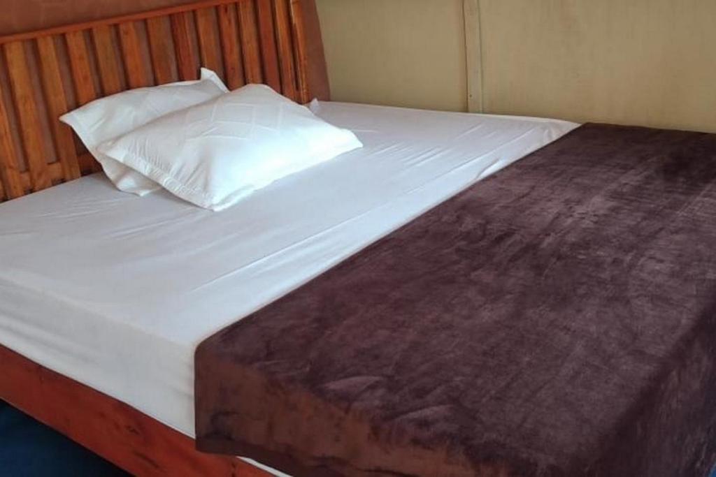 a large bed with white sheets and a pillow at Penginapan puncak Dua Mitra RedDoorz in Berastagi