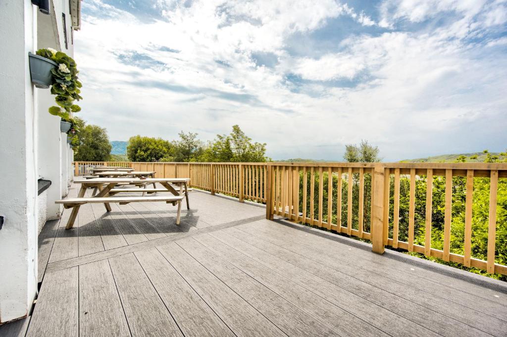 a wooden deck with a picnic table and tables on it at The Morar Hotel in Morar