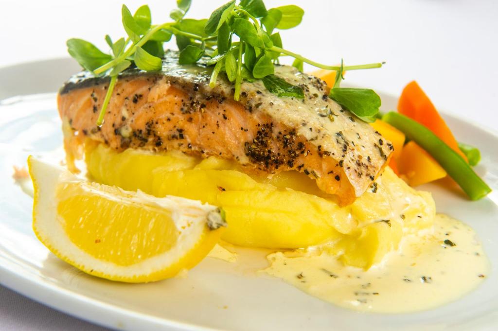 a plate of food with a piece of fish and fruit at The Morar Hotel in Morar