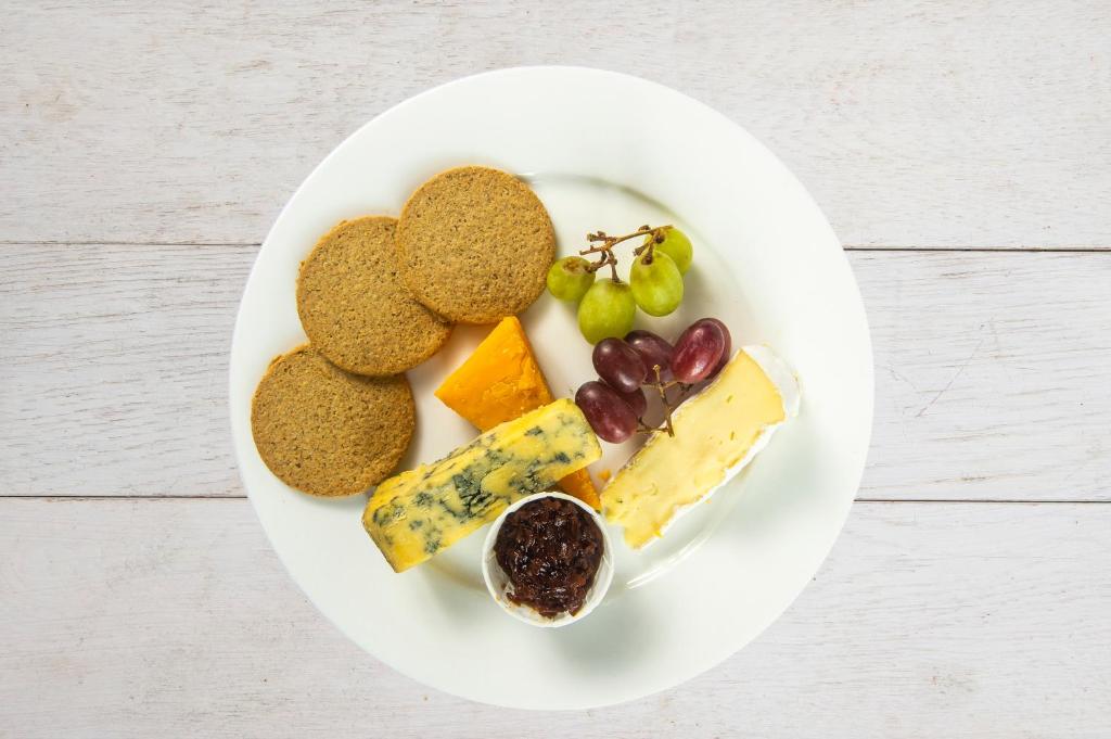 a plate of food with cheese and fruit on it at The Morar Hotel in Morar