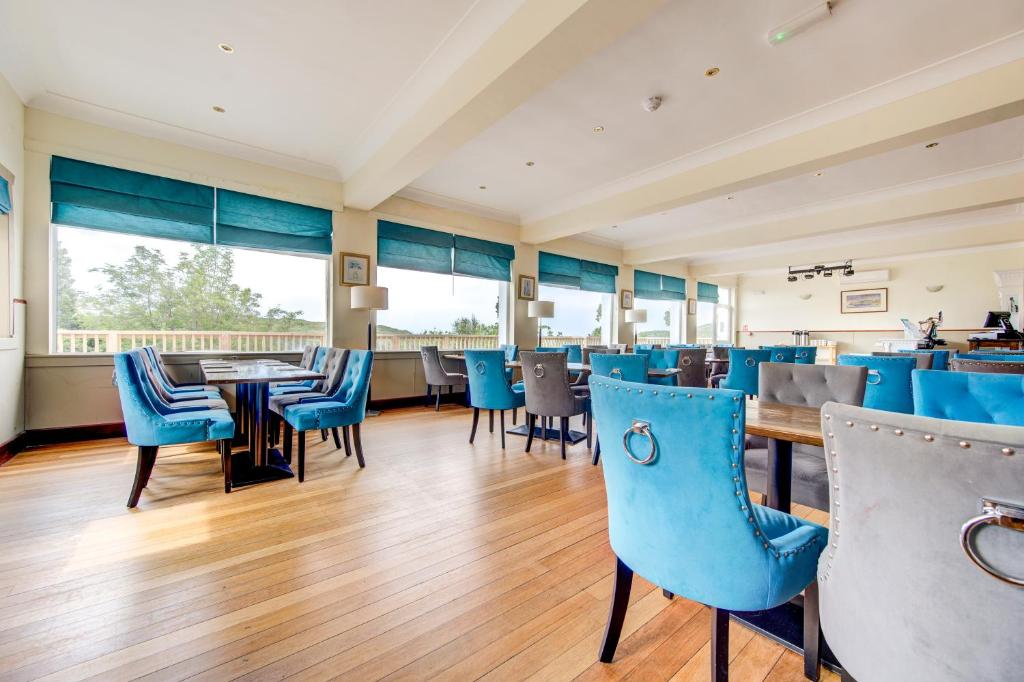 a dining room with blue chairs and tables at The Morar Hotel in Morar