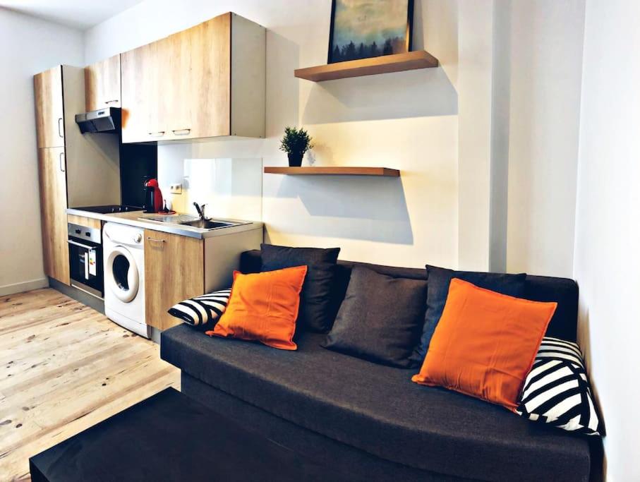 - un salon avec un canapé noir et des oreillers orange dans l'établissement Charmant T2 cosy à deux pas du centre, à Bayonne