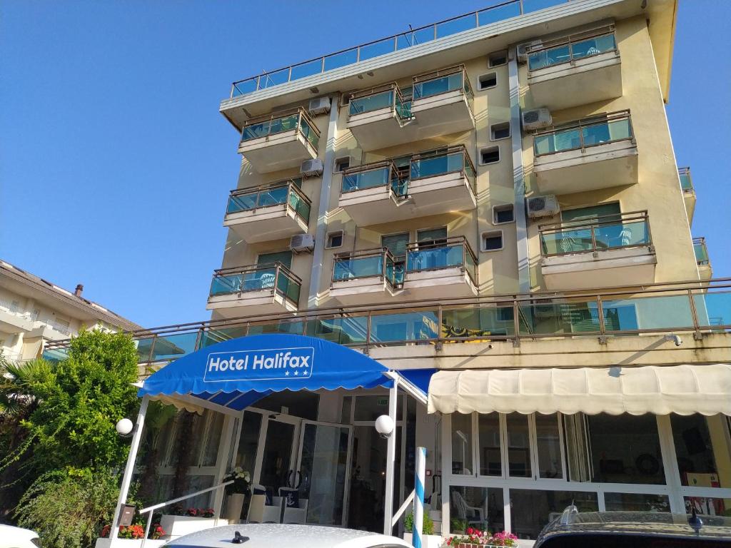 a hotel building with a blue umbrella in front of it at Hotel Halifax in Lido di Jesolo