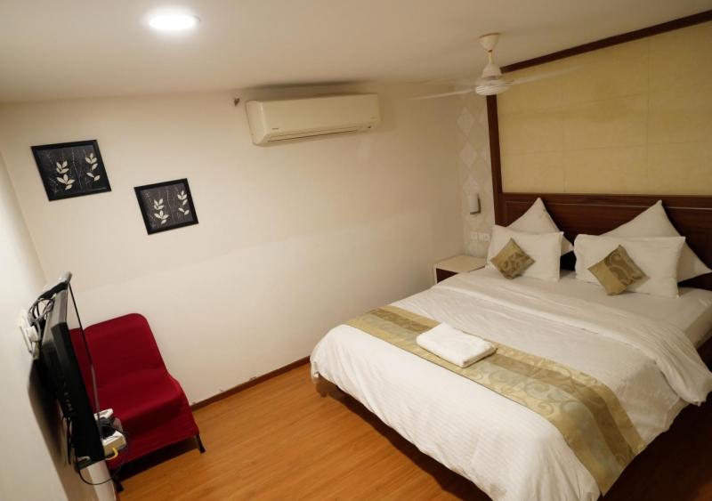 a bedroom with a bed and a red chair at Hotel Sasya Pride in Kurnool