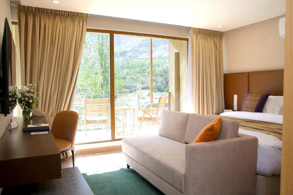Habitación de hotel con cama, sofá y ventana en Ambiance Resort Hunza, en Hunza