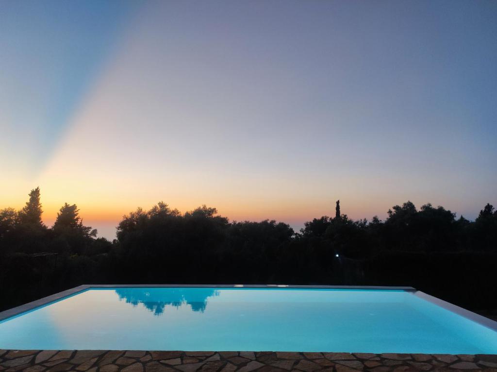 una piscina con puesta de sol en el fondo en Kalliope Apartments, en Tsoukaladhes